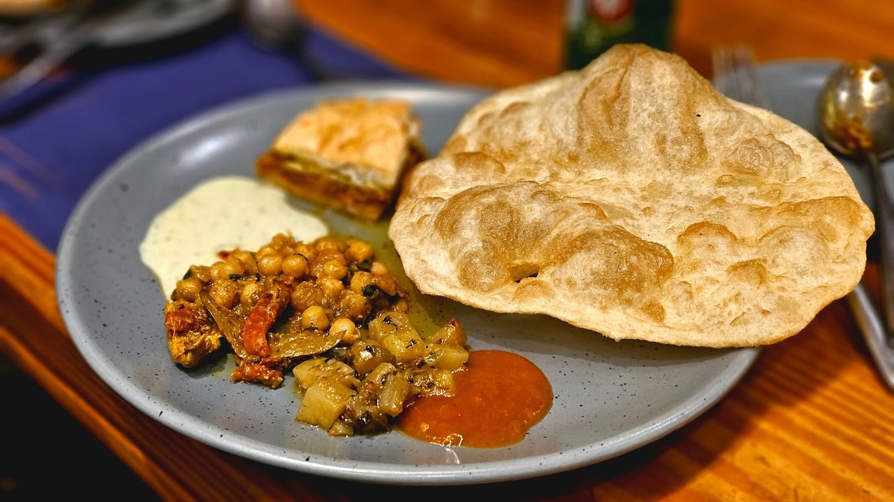 A delicious Indian meal featuring puri, chole, and chutneys served on a blue plate.