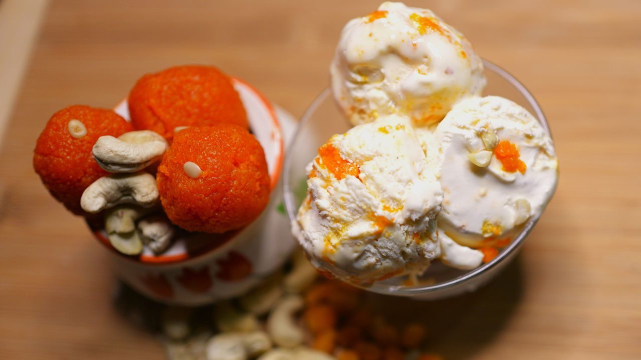 Top view of Indian laddoos and ice cream with cashews on a wooden surface.